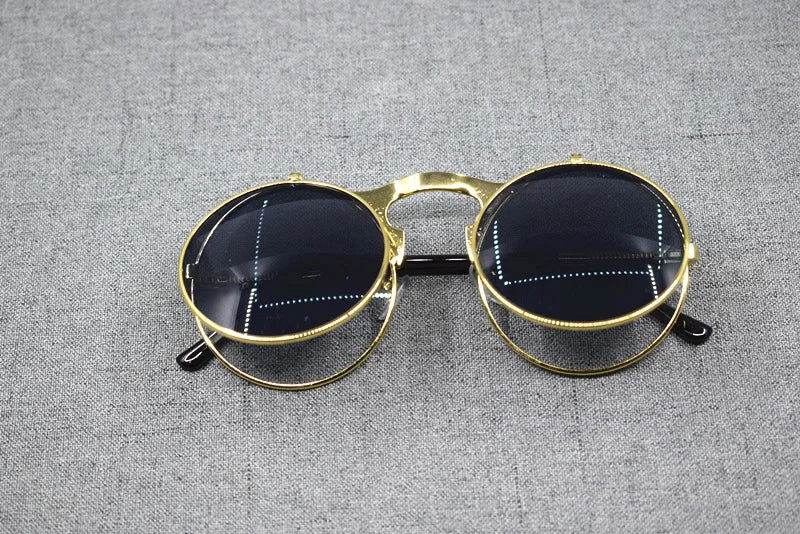 Sunglass Lover flip up sunglasses gold round metal frame with dark lenses on gray fabric background