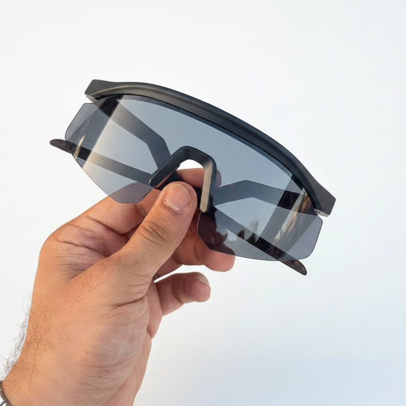 Hand holding a pair of sunglasses with a blurred background