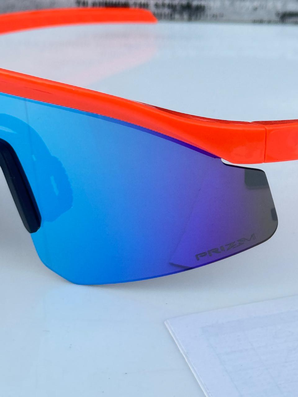 Sunglasses with blue lenses and orange frame on a white surface