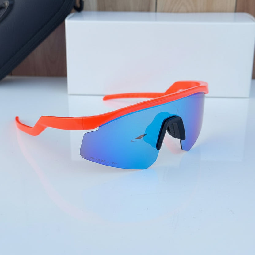 Orange-framed sunglasses with blue lenses on a white surface