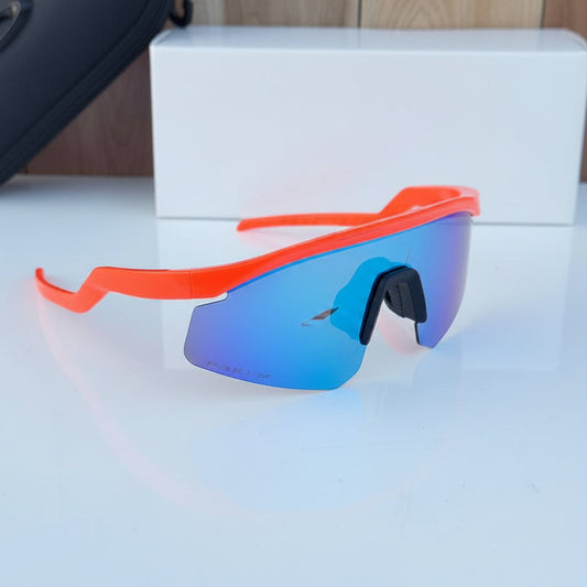 Orange-framed sunglasses with blue lenses on a white surface