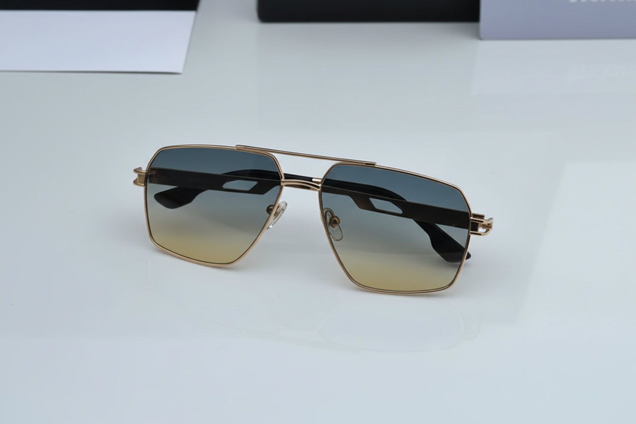 Gold-framed sunglasses with gradient lenses on a white surface