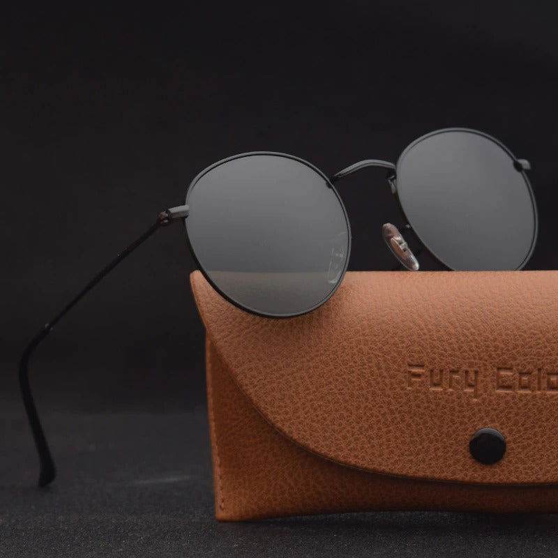 Sunglass Lover black metal frames with dark lenses vintage round sunglasses for men and women. resting on brown leather case