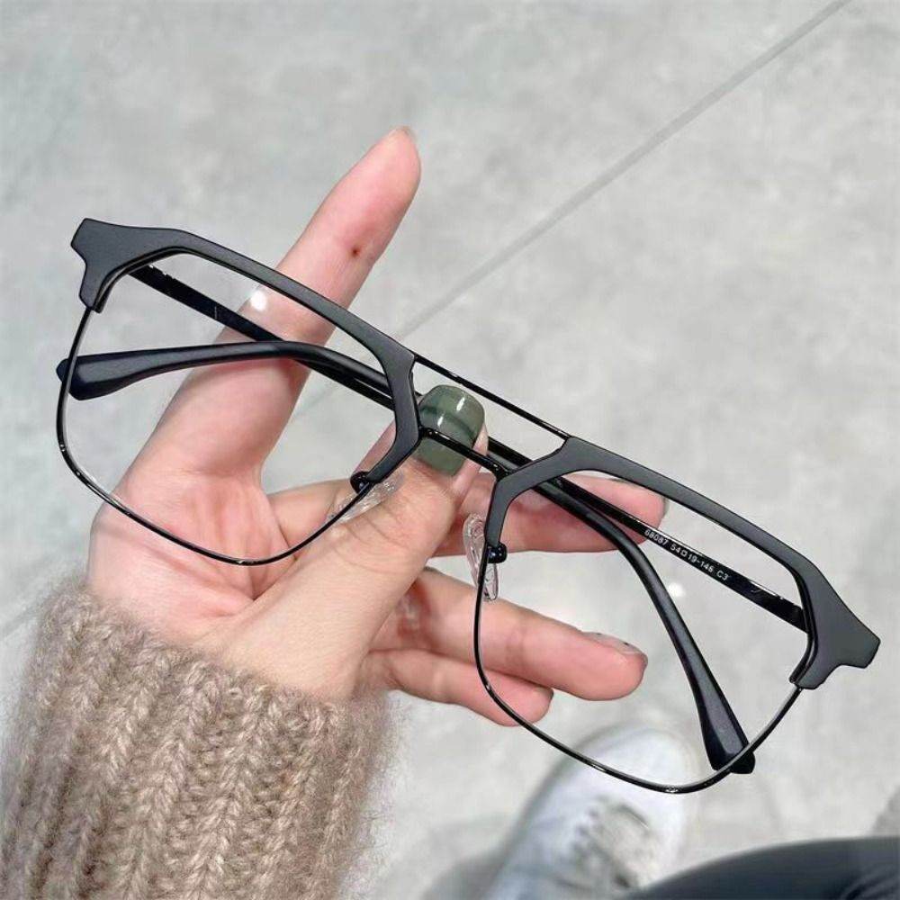 Sunglass Lover anti-blue light glasses for men black angular metal frame held in hand on gray background