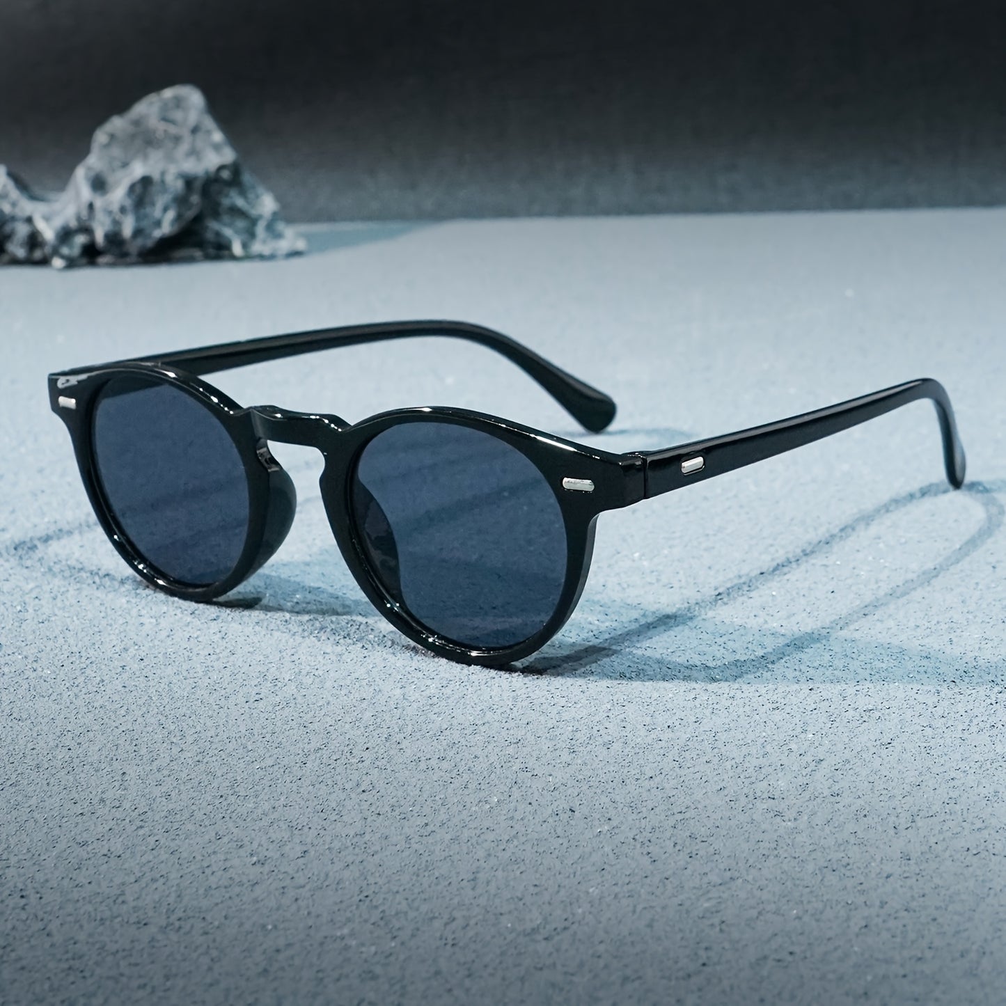 Black sunglasses on a textured surface with a blurred natural background
