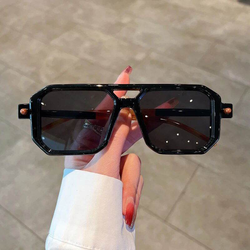 Sunglass Lover black oversized geometric frames with dark gradient lenses held by hand unisex square gradient sunglasses