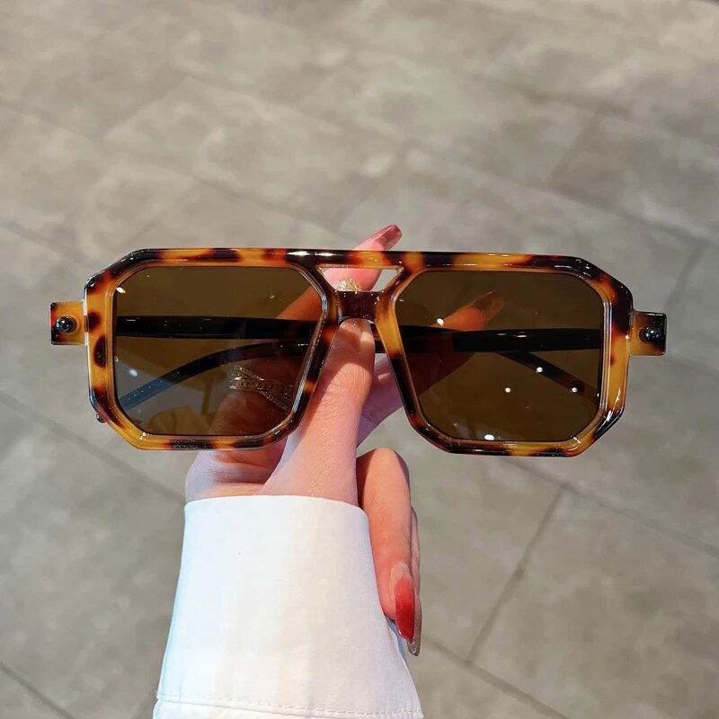 Sunglass Lover tortoiseshell frames with brown lenses held by hand unisex square gradient sunglasses