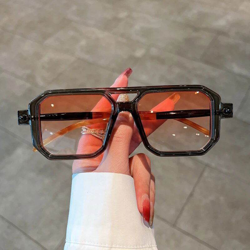 Hand holding Sunglass Lover unisex square gradient sunglasses with amber gradient lenses and dark geometric frame
