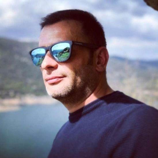 Sunglass Lover polarized square wayfarer sunglasses worn by man with blue mirrored lenses reflecting lake and mountains