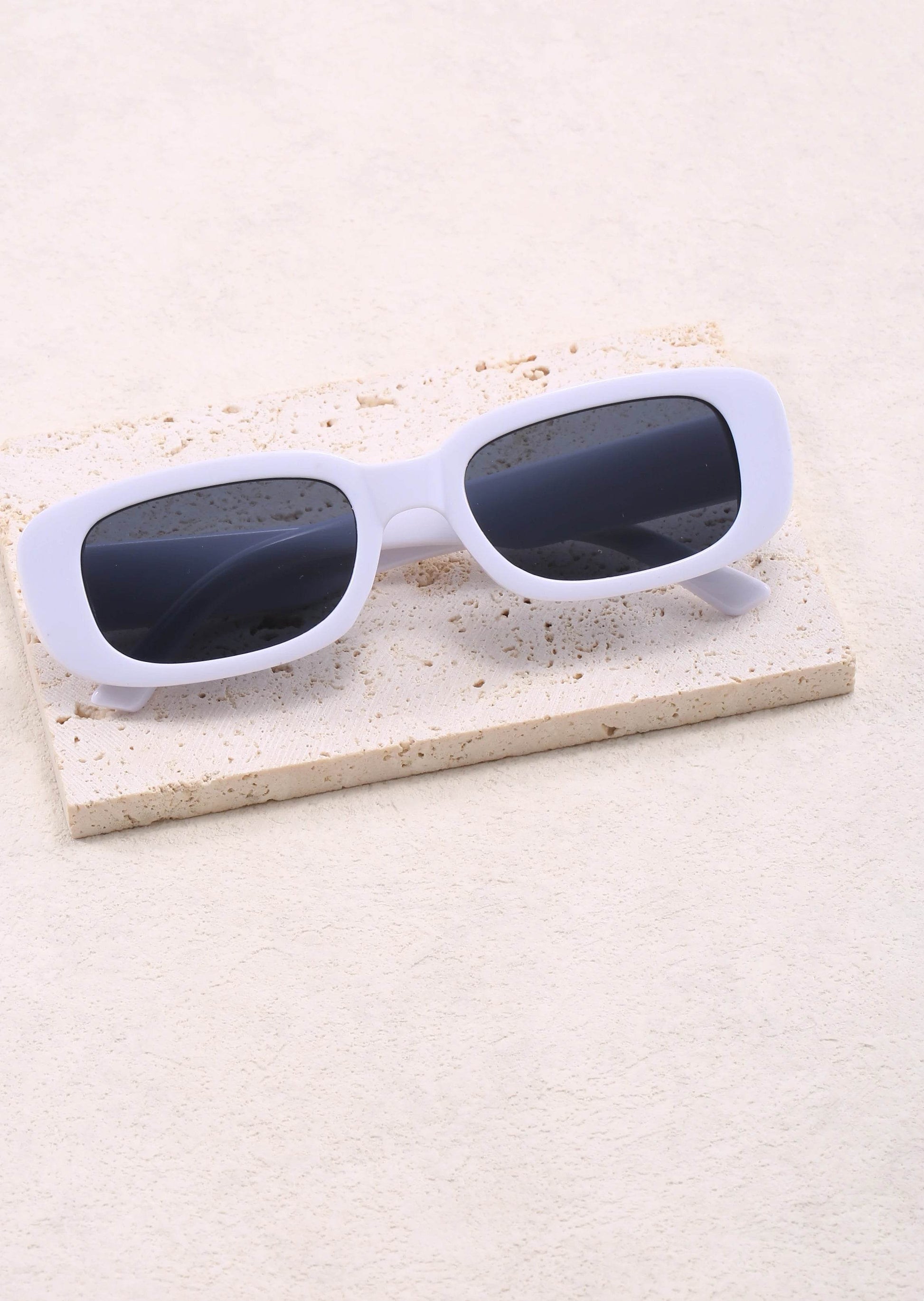 Sunglass Lover Jimmy Rectangle sunglasses white chunky frame with dark lenses on textured stone prop