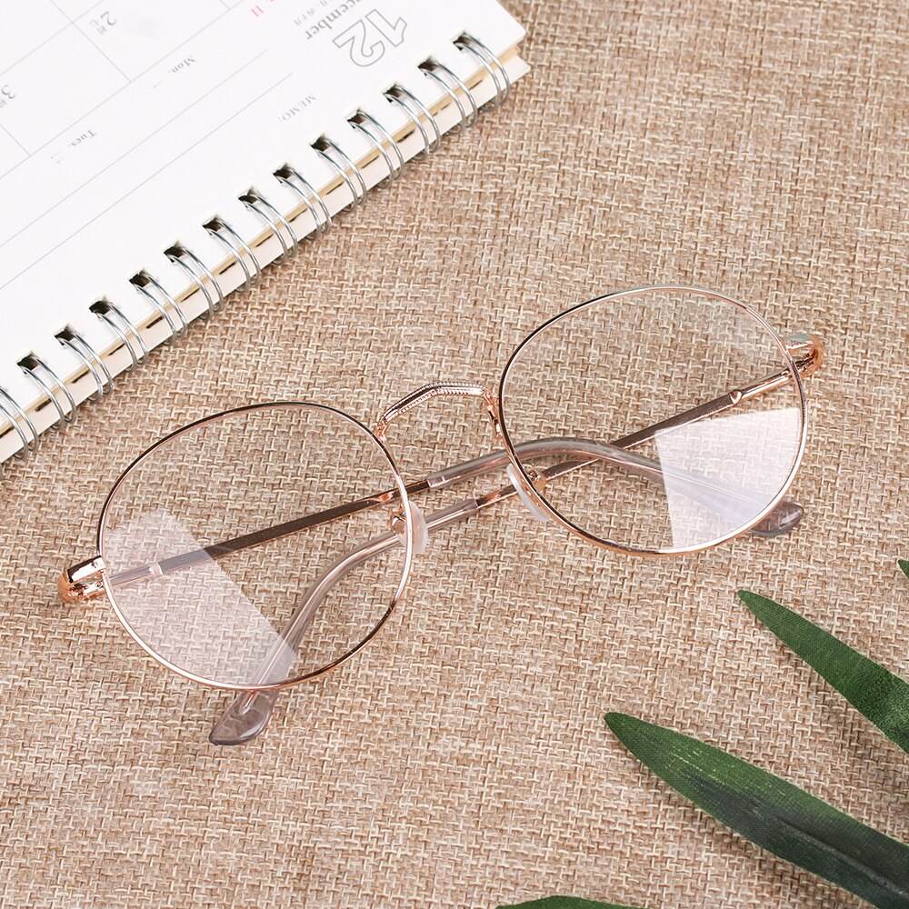 Sunglass Lover COM rose gold round metal frame reading glasses on textured beige mat with notebook