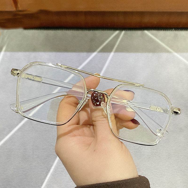 Sunglass Lover oversized square metal eyeglasses frames in gold with clear lenses held in hand