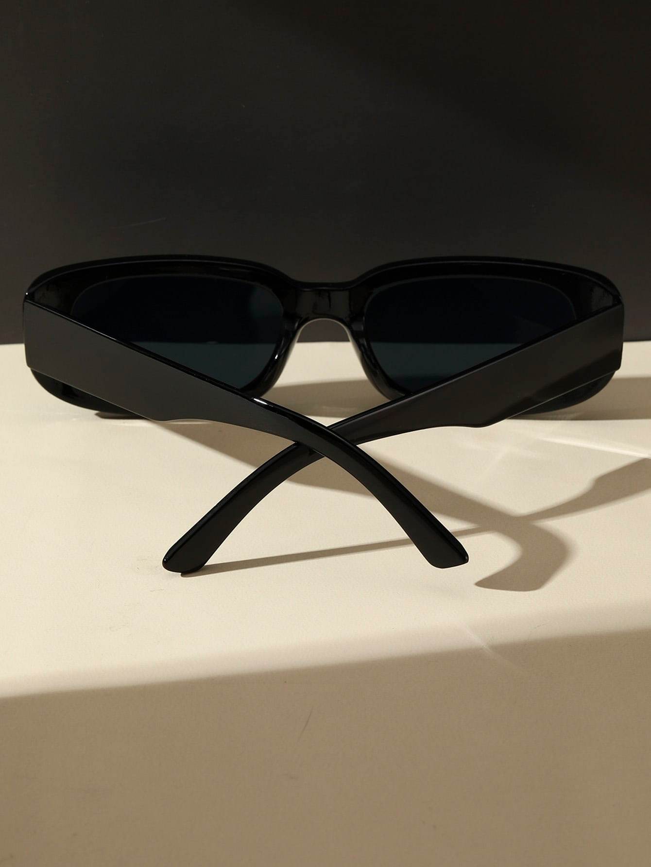 Sunglass Lover black small rectangle sunglasses with dark lenses and crossed temples on a neutral background