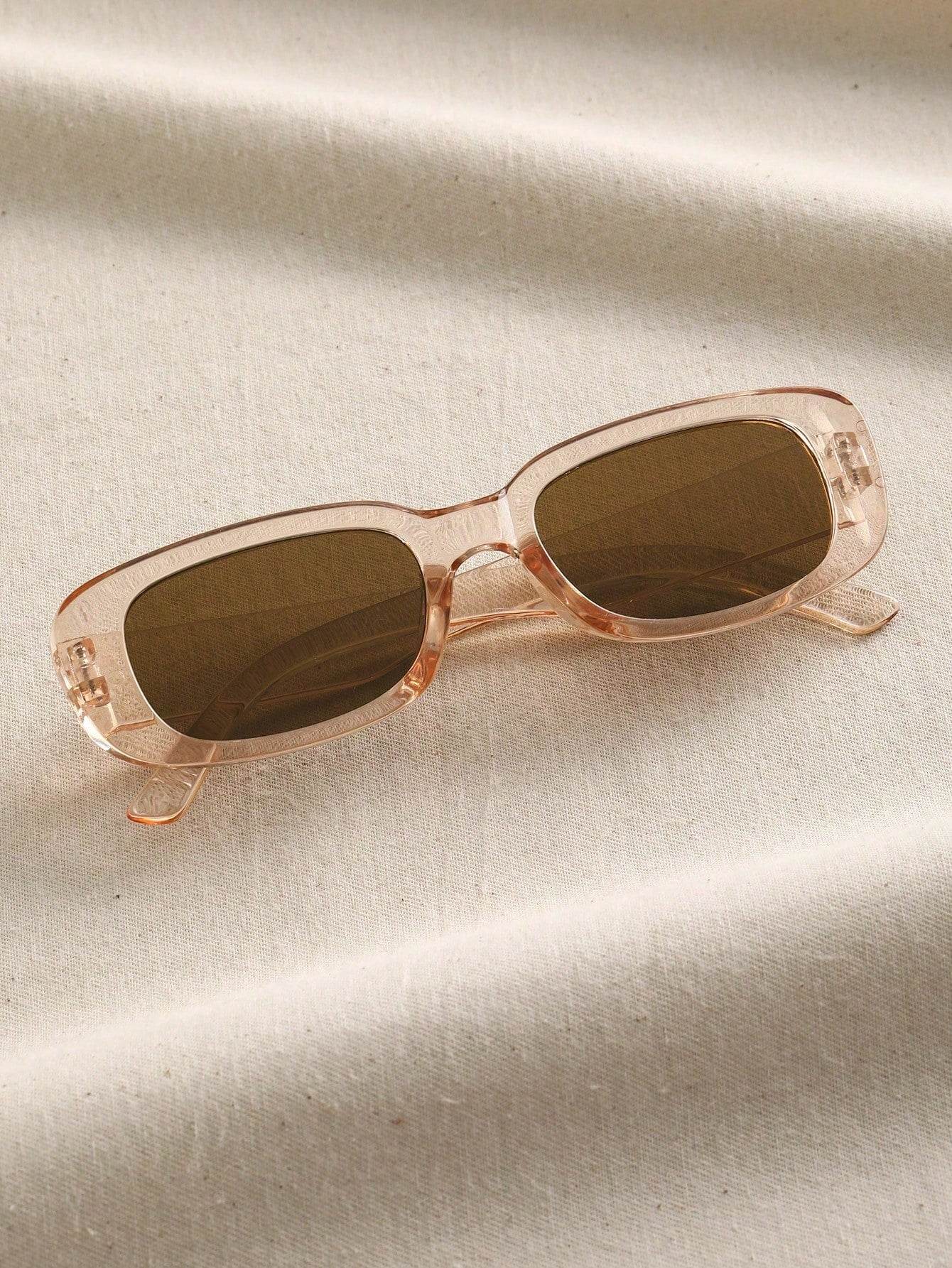 Sunglass Lover peach translucent frame small rectangle sunglasses with brown lenses laid on textured fabric