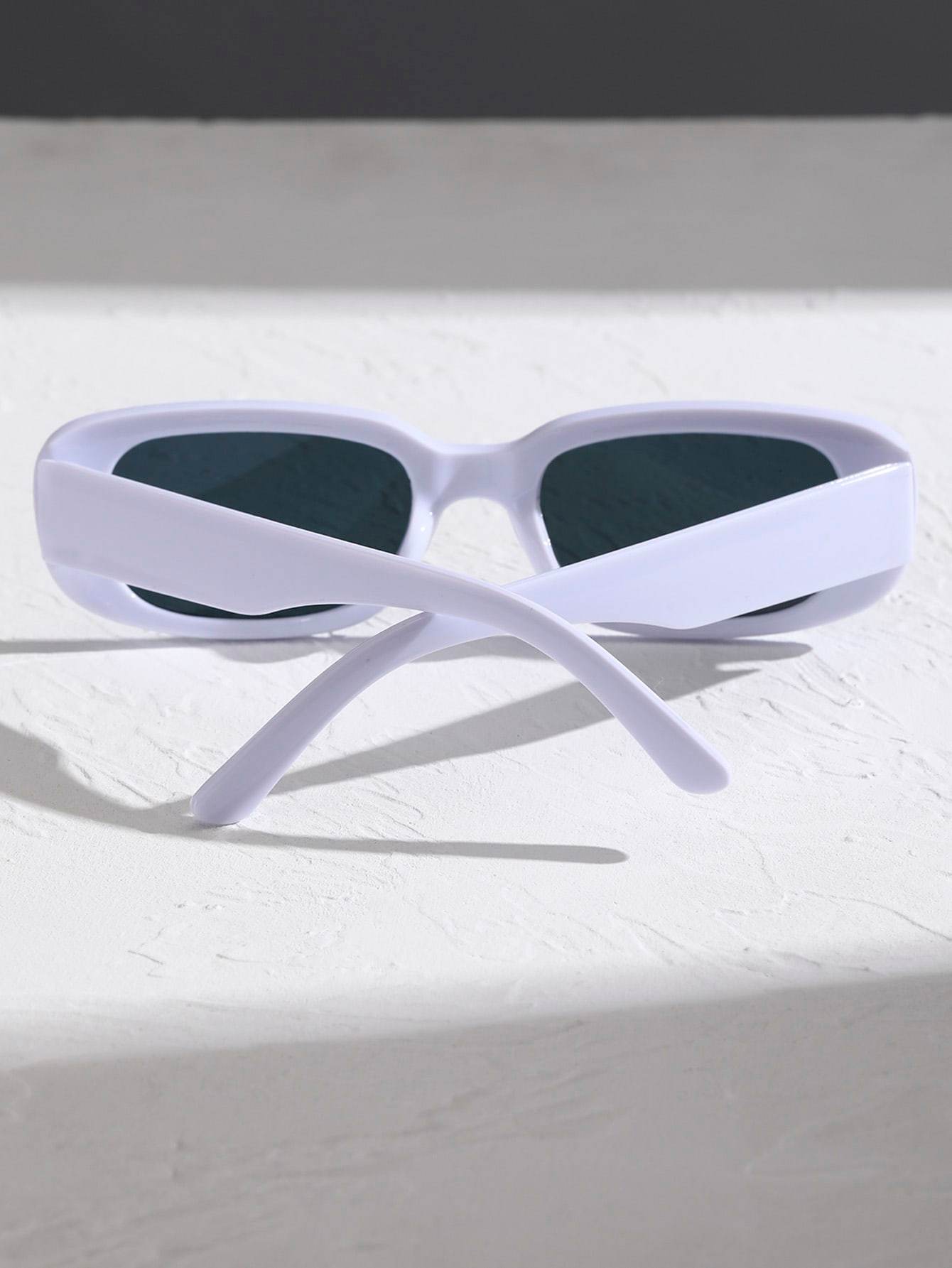 Sunglass Lover white small rectangle sunglasses folded with crossed temples dark lenses on textured white surface