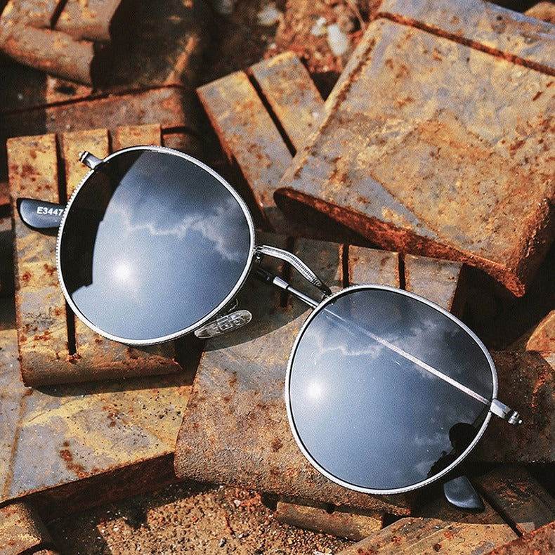 Sunglass Lover silver metal round sunglasses for men and women with mirrored lenses on rusted metal bricks