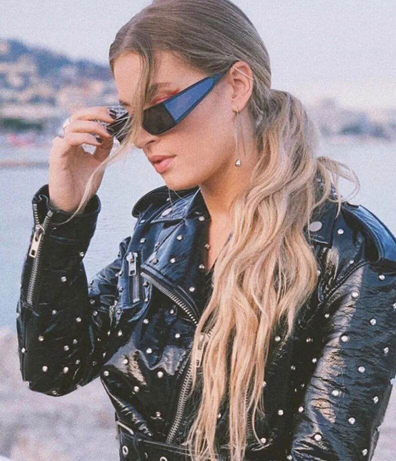 Sunglass Lover wearing retro rectangle sunglasses for women blue mirror lenses long blonde hair studded leather jacket