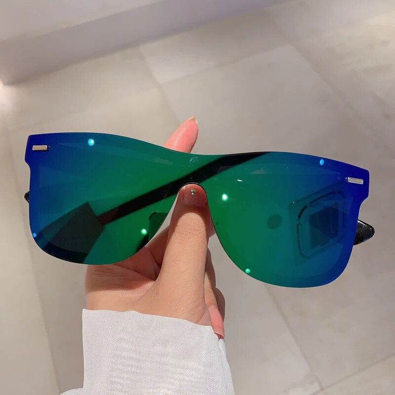 Sunglass Lover rimless oversized square sunglasses with blue green mirrored lenses held in hand