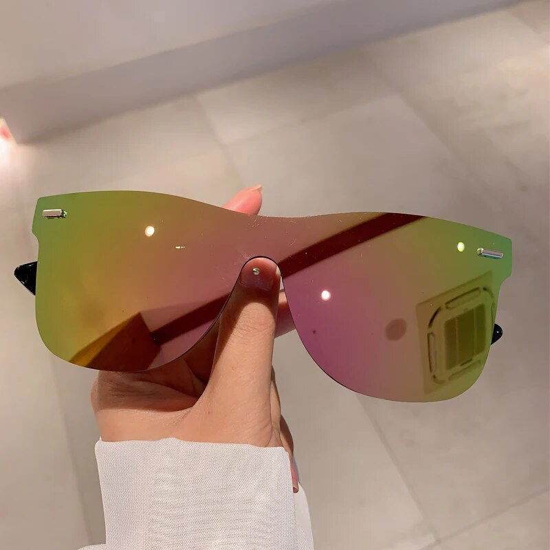 Sunglass Lover rimless oversized square sunglasses with pink green mirrored lenses held by hand