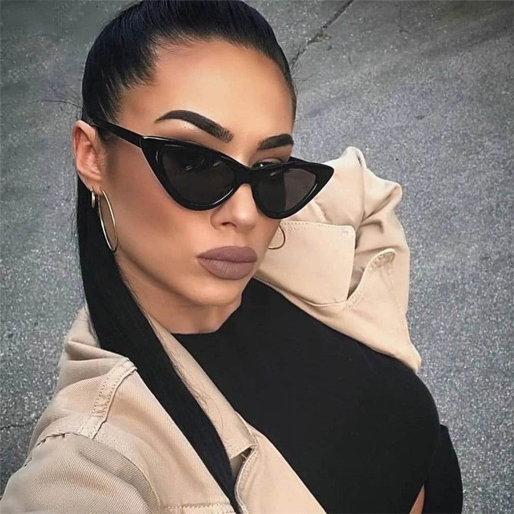 Sunglass Lover model wearing black small cat eye sunglasses trendy with hoop earrings beige jacket