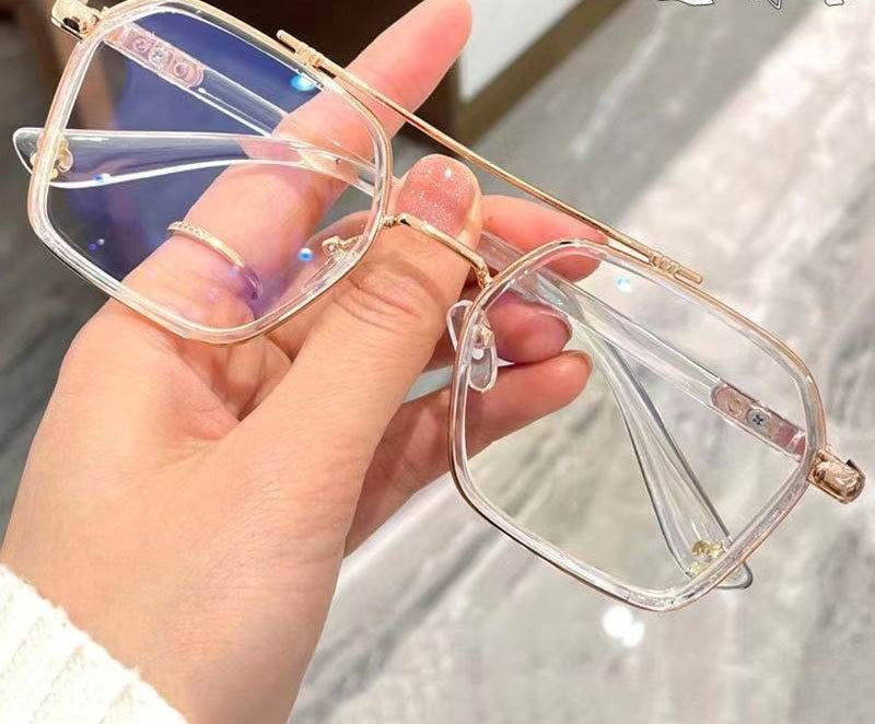 Sunglass Lover clear square frames with gold metal bridge and temples punk style blue light blocking eyeglasses held in hand