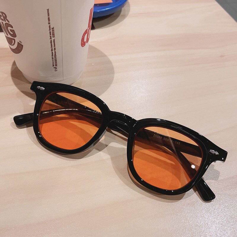 Sunglass Lover black frame sunglasses with orange lenses on table vintage round sunglasses for men and women.
