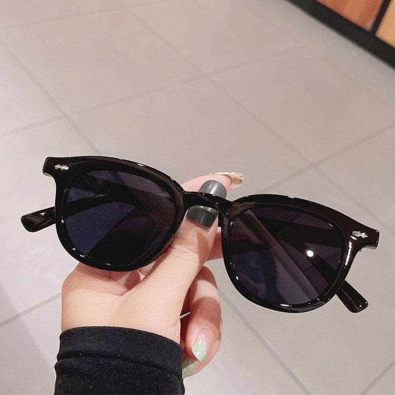 Sunglass Lover black glossy frame vintage round sunglasses for men and women held by hand